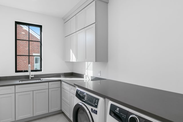 washroom with cabinets, washer and clothes dryer, and sink