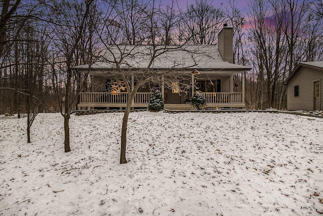 snow covered property with covered porch