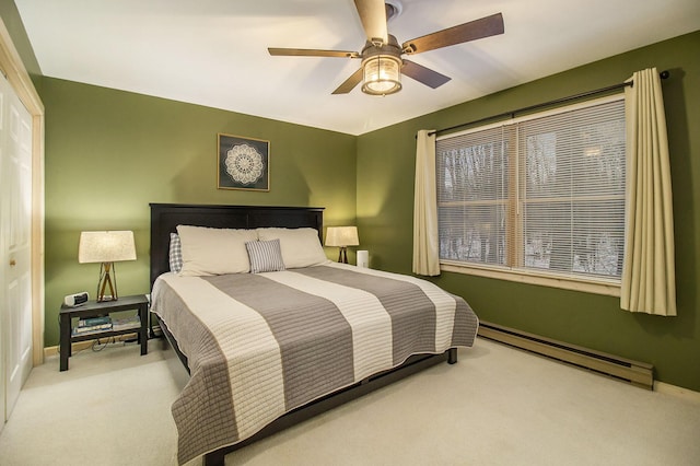 carpeted bedroom with ceiling fan, a closet, and a baseboard heating unit