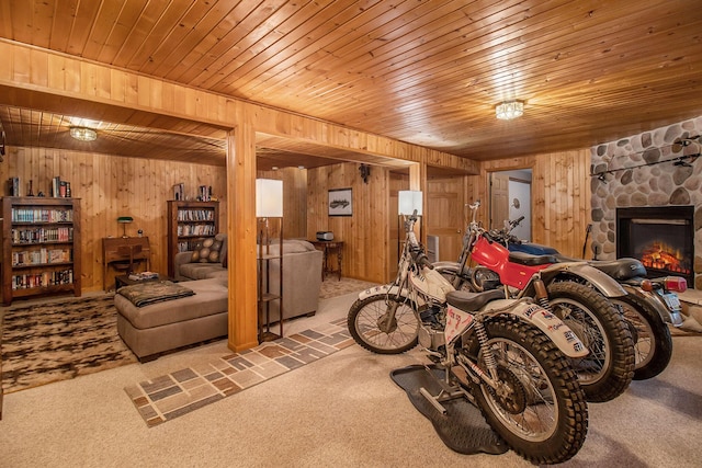 interior space with wooden ceiling, a stone fireplace, wooden walls, and light carpet