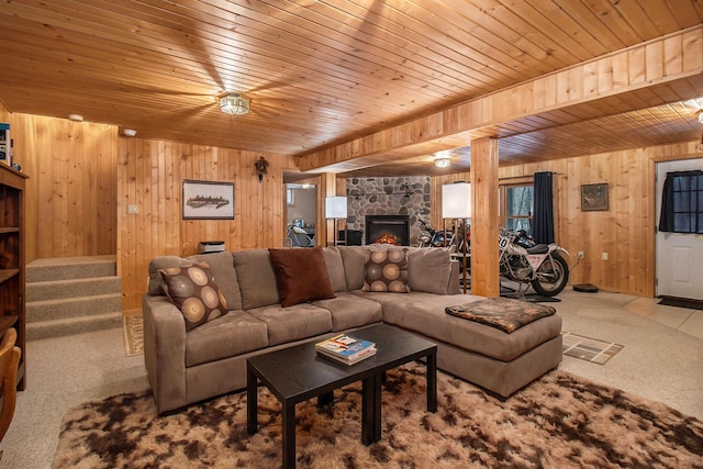 living room featuring wooden ceiling, a fireplace, wood walls, and light colored carpet