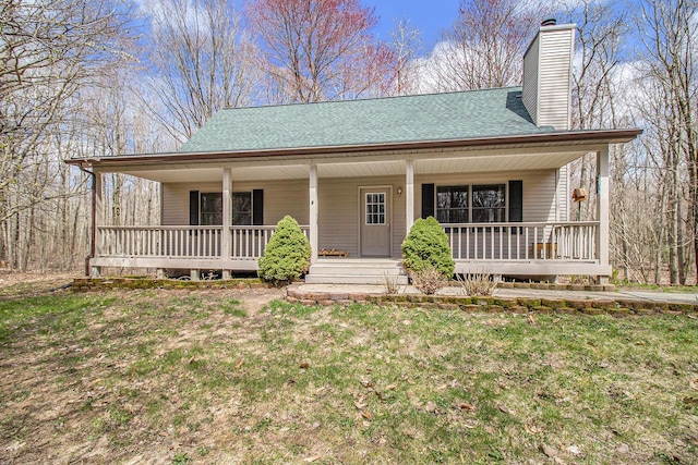 4714 N Lincoln Rd, Ludington, MI 49431 - view of front of house featuring a porch, roof with shingles, a front yard, and a chimney