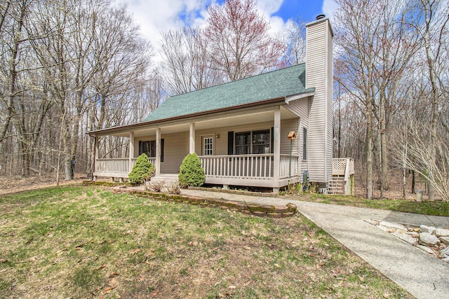 4714 N Lincoln Rd, Ludington, MI 49431 - view of front of home with covered porch, a chimney, roof with shingles, and a front lawn