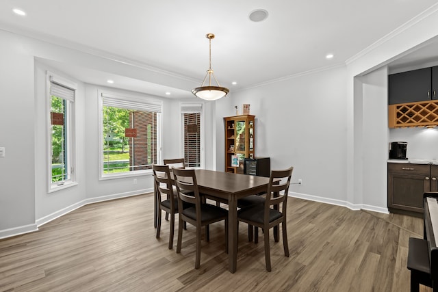 dining room with light wood-type flooring, bar, and ornamental molding