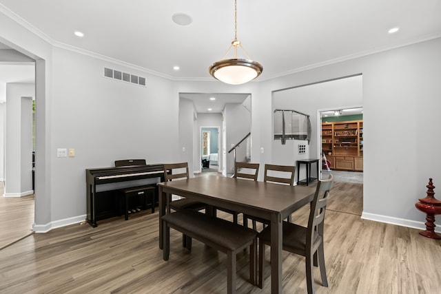 dining space with hardwood / wood-style flooring and crown molding