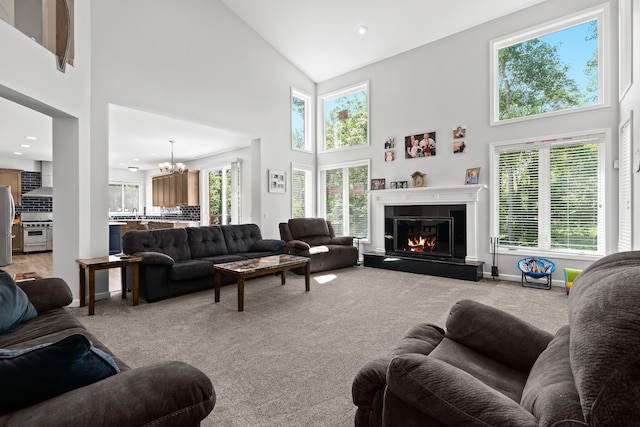 carpeted living room featuring plenty of natural light, high vaulted ceiling, and an inviting chandelier