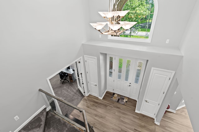 foyer entrance featuring a towering ceiling, a notable chandelier, and hardwood / wood-style flooring