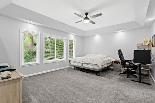 carpeted bedroom featuring ceiling fan and a tray ceiling