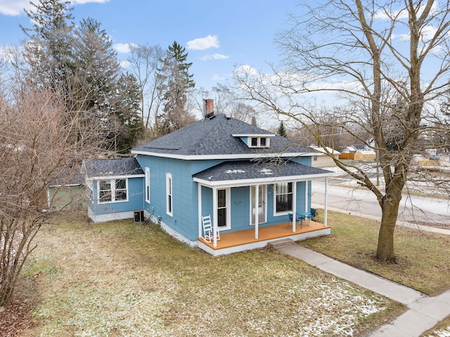 bungalow featuring cooling unit, a front lawn, and covered porch