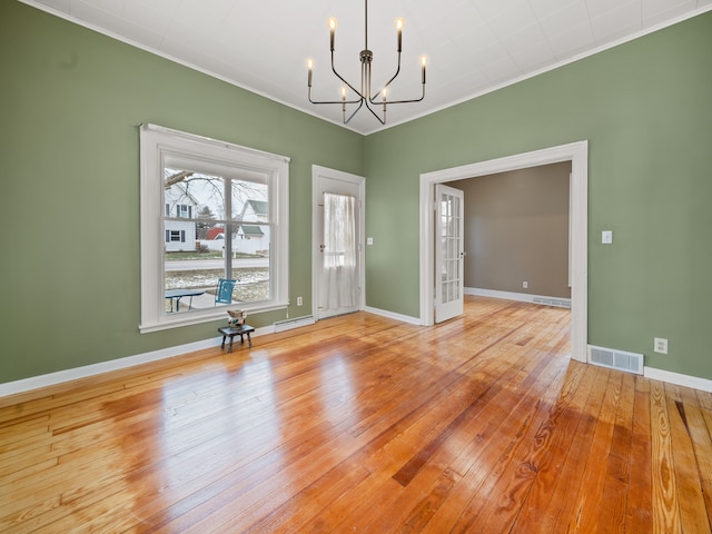 spare room featuring light hardwood / wood-style flooring, ornamental molding, and an inviting chandelier