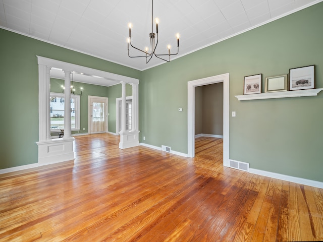 unfurnished dining area with light wood-type flooring, ornate columns, crown molding, and a chandelier