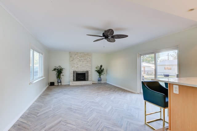 unfurnished living room with ceiling fan, a fireplace, a wealth of natural light, and light parquet floors