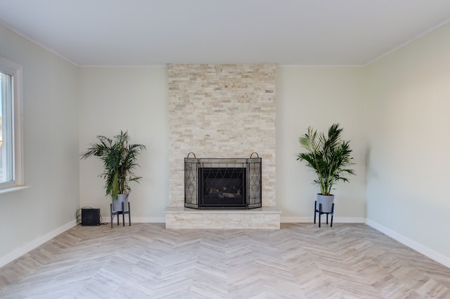 unfurnished living room featuring crown molding, a fireplace, and light parquet floors