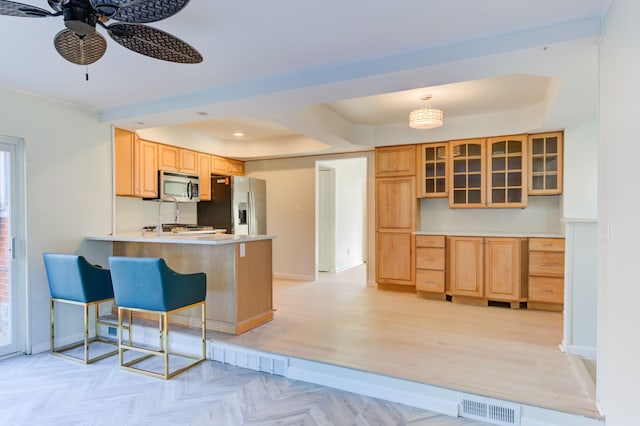 kitchen featuring kitchen peninsula, a kitchen breakfast bar, stainless steel appliances, ceiling fan, and pendant lighting