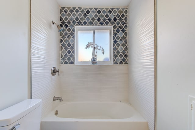 bathroom featuring toilet and tiled shower / bath