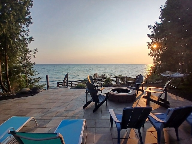 patio terrace at dusk with a fire pit and a water view