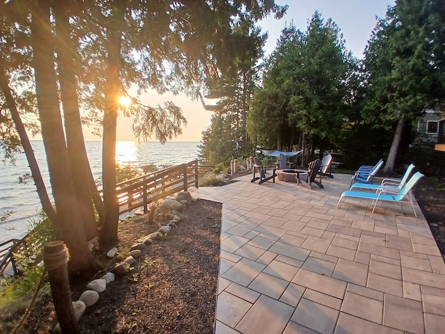 view of patio featuring an outdoor fire pit, fence, and a water view