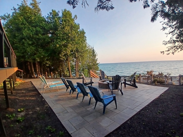 view of patio / terrace with a water view, fence, and an outdoor fire pit