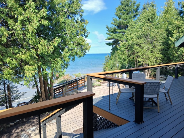 wooden terrace with a water view and outdoor dining space