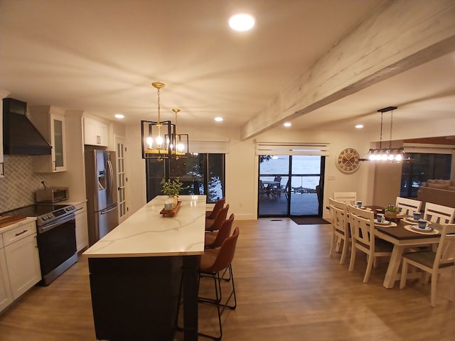 kitchen with a kitchen island, light stone countertops, premium range hood, appliances with stainless steel finishes, and an inviting chandelier