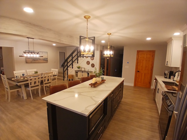 kitchen with recessed lighting, white cabinets, a center island, and light wood-style floors