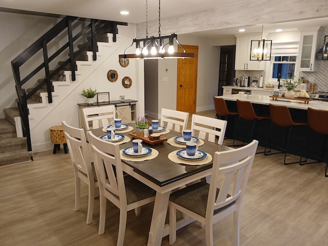 dining room featuring baseboards, light wood-style floors, and stairs