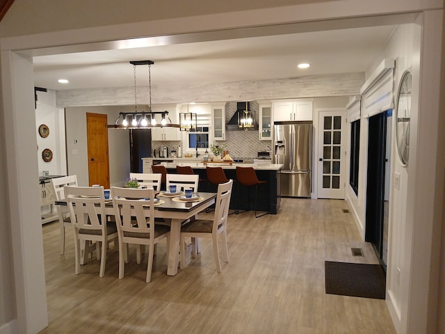 dining room with recessed lighting, light wood-type flooring, visible vents, and beamed ceiling