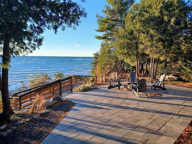 view of home's community with a patio area, a water view, and an outdoor fire pit