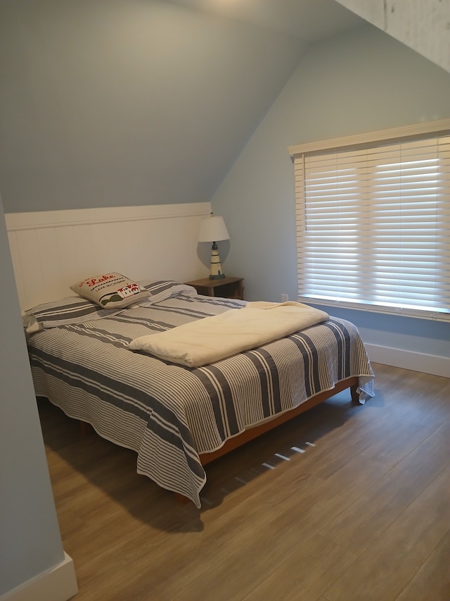 bedroom with wood finished floors and vaulted ceiling