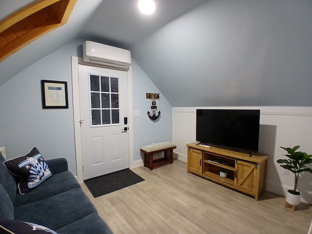 living area featuring light wood finished floors, a wall unit AC, and vaulted ceiling