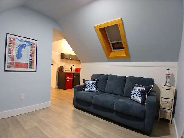 living room featuring light wood finished floors, baseboards, and vaulted ceiling