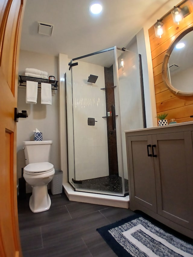 bathroom featuring visible vents, wood finished floors, toilet, and a stall shower