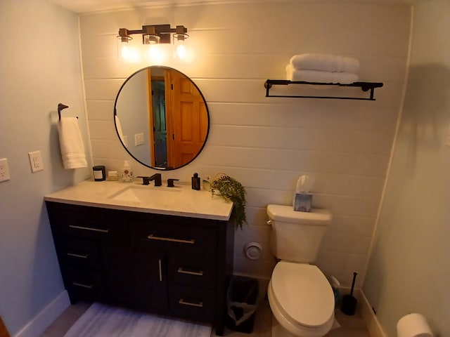 half bath with toilet, vanity, and baseboards