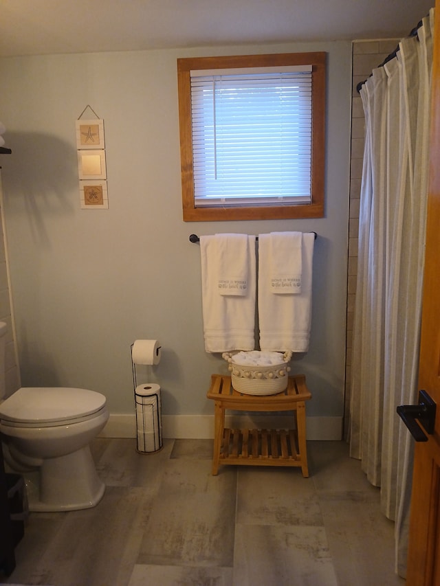 full bathroom featuring a shower with curtain, toilet, and baseboards