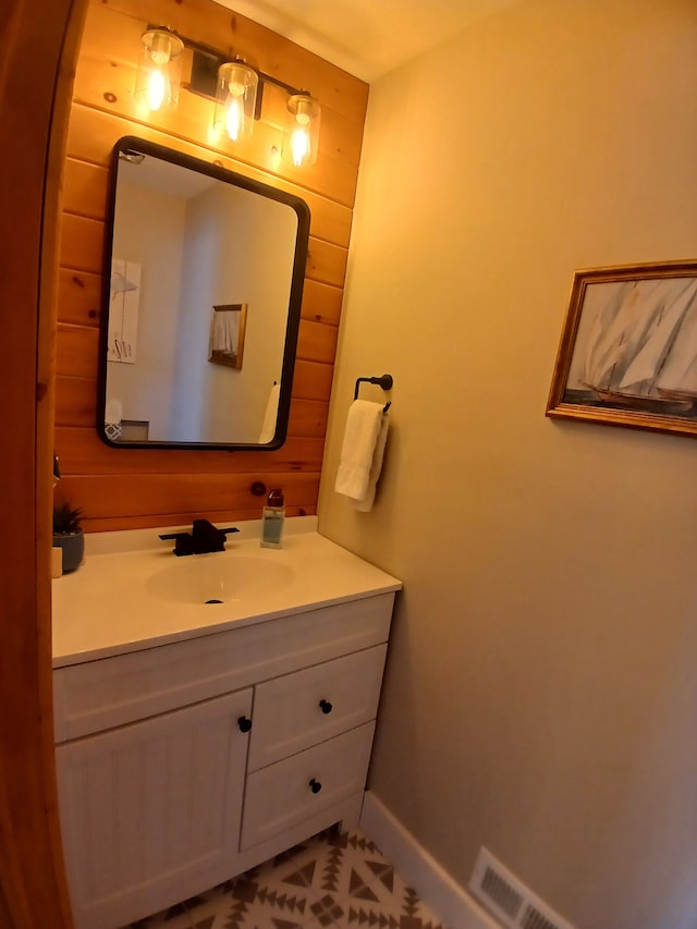 bathroom featuring visible vents, wood walls, vanity, and baseboards