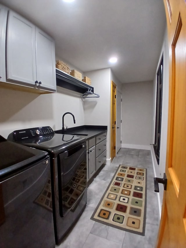 washroom with washing machine and clothes dryer, cabinet space, baseboards, and a sink