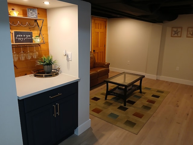 living room featuring recessed lighting, baseboards, a bar, and light wood finished floors