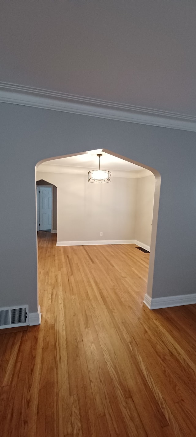 empty room with light hardwood / wood-style flooring and ornamental molding