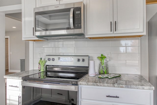 kitchen featuring light stone countertops, appliances with stainless steel finishes, white cabinets, and backsplash