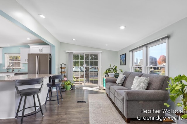 living room with dark hardwood / wood-style floors, a healthy amount of sunlight, and vaulted ceiling