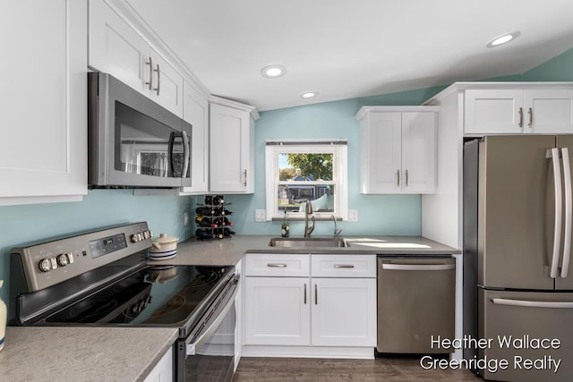 kitchen with sink, vaulted ceiling, appliances with stainless steel finishes, dark hardwood / wood-style flooring, and white cabinetry