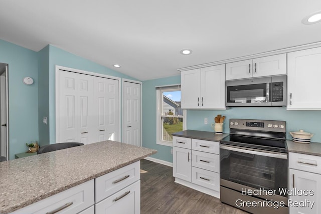 kitchen featuring vaulted ceiling, stainless steel appliances, white cabinetry, and dark hardwood / wood-style floors