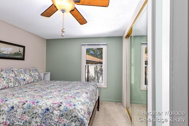 bedroom featuring a textured ceiling, light colored carpet, and ceiling fan