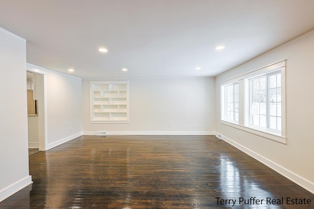 spare room with built in shelves and dark wood-type flooring