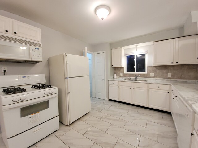 kitchen with white appliances, sink, backsplash, and white cabinetry