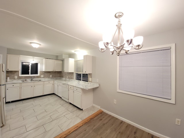 kitchen with sink, hanging light fixtures, backsplash, white dishwasher, and white cabinets