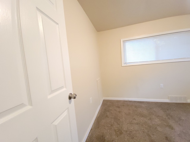 carpeted empty room featuring lofted ceiling