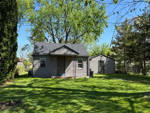 1095 Harding Dr, Grand Blanc, MI 48507 - back of house featuring a lawn, an outdoor structure, and roof with shingles