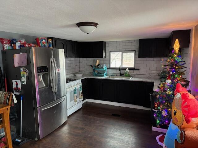 kitchen featuring sink, stainless steel fridge, backsplash, and gas range gas stove