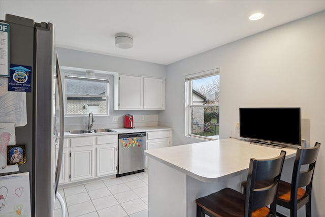 kitchen featuring white cabinets, a kitchen breakfast bar, sink, kitchen peninsula, and stainless steel appliances